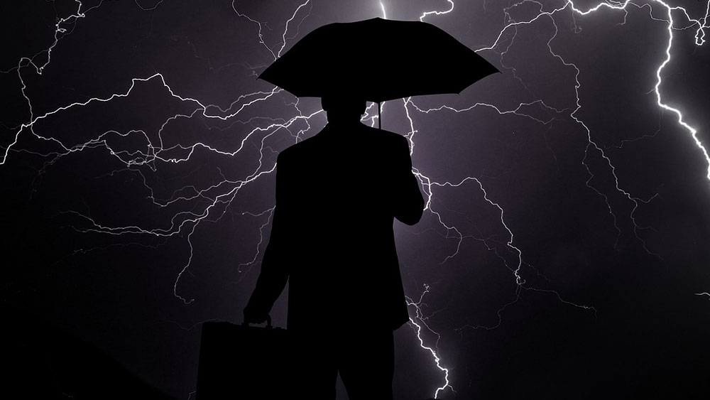 Picture of person holding an umbrella over lightning-lit sky.