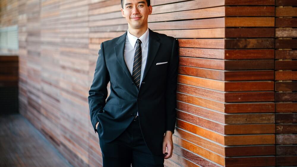 Smiling young Asian man in business suit.