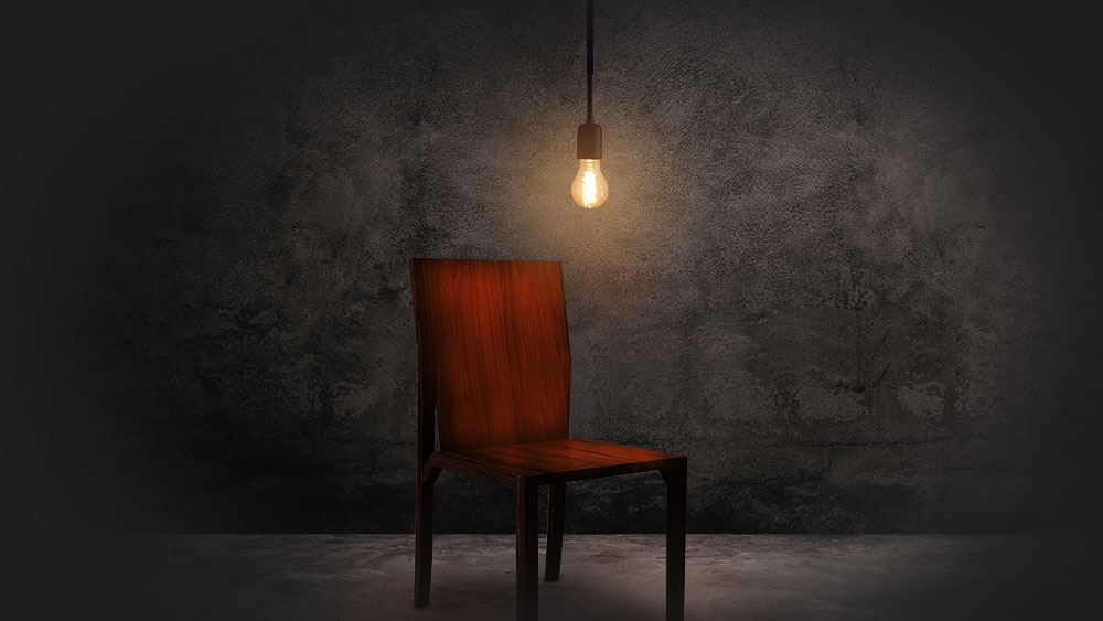 Picture of a dimly lit room with a red interrogation chair.