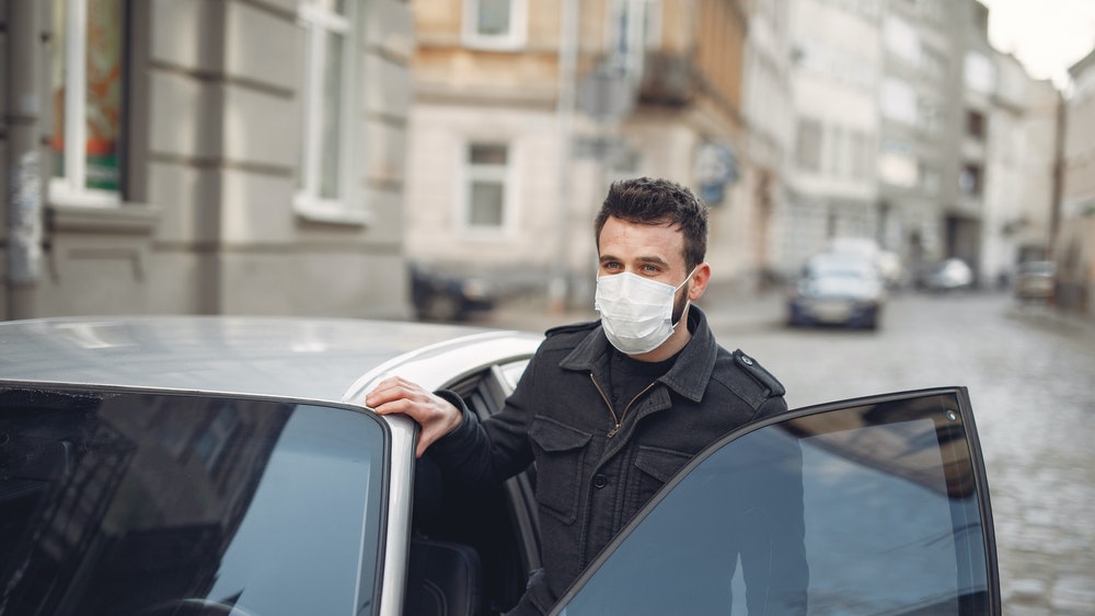 Bearded man with mask getting out of car